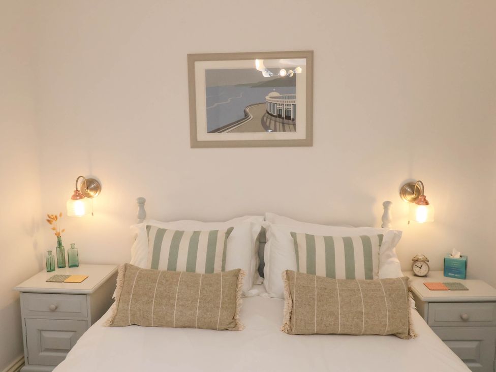 A bedroom with a bed flanked by two nightstands each with lamps and decor at The Riddle in Whitby