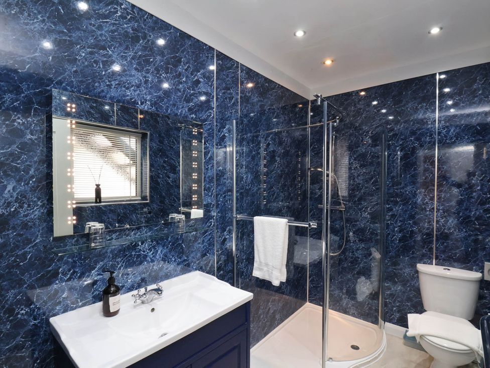 A bathroom with a sink cabinet a mirror a shower with glass doors and a toilet at The Riddle in Whitby