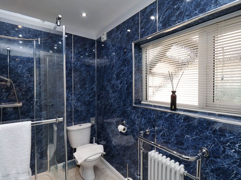 A bathroom with a shower enclosure toilet radiator and window with blinds at The Riddle in Whitby