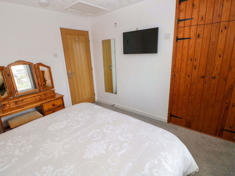 A bedroom with a bed, vanity, TV, and wardrobe at Ty'r Winllan, Newport, Pembrokeshire