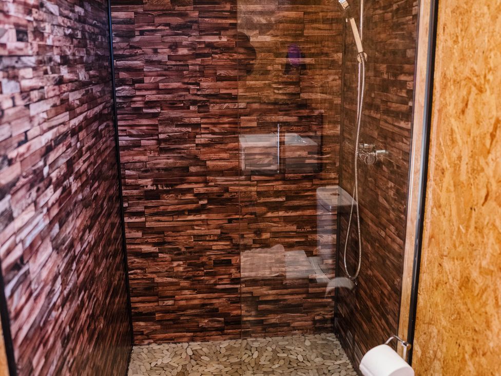 A shower with a glass door and stone floor at The Chard in Longtown