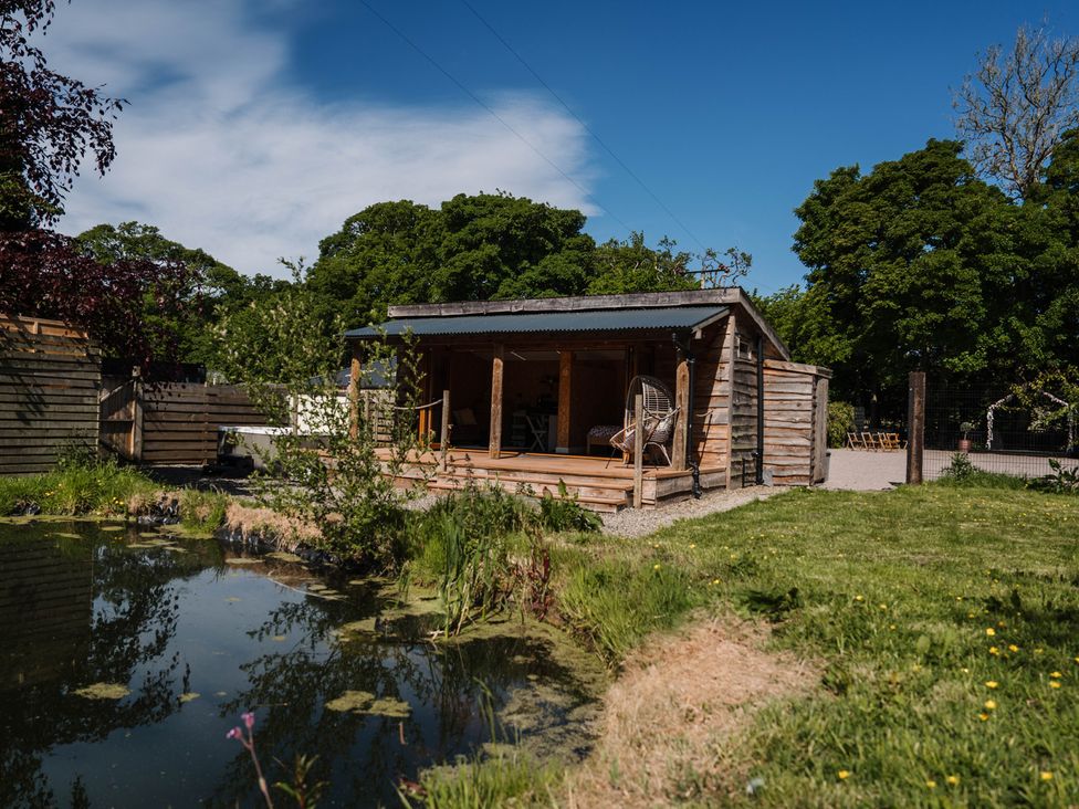 A shed near water with grass and trees at The Chard in Longtown