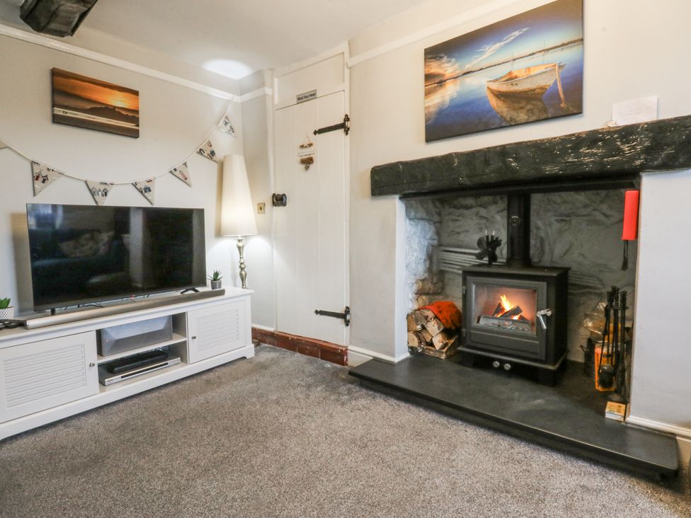 A living room with a television and fireplace at Tan Yr Allt Chwilog