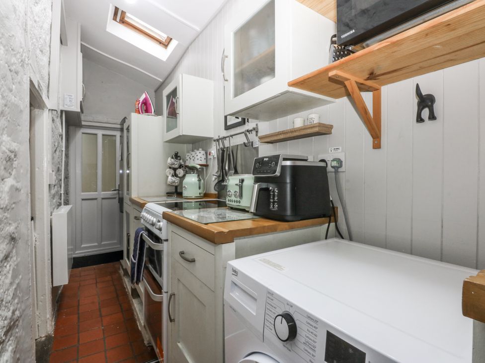 A kitchen with a washing machine and stove at Tan Yr Allt in Chwilog