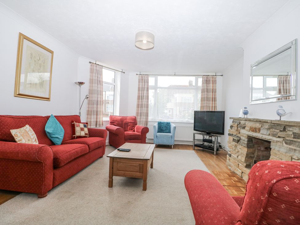 A living room with red sofas and a wooden coffee table at Sea Dreams in Goring-By-Sea