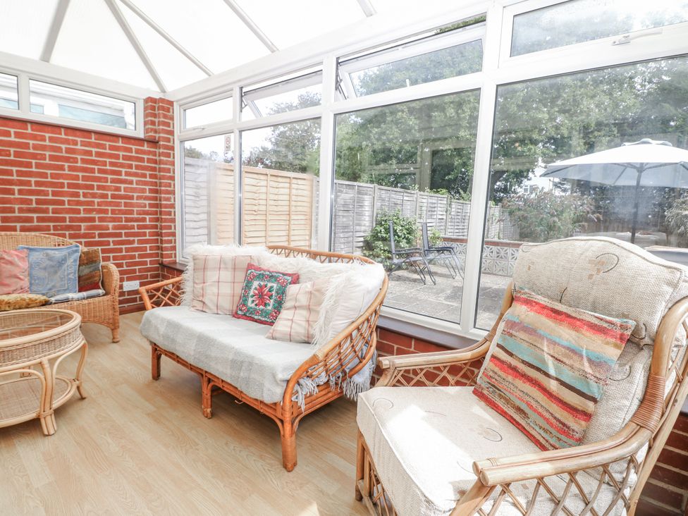 A conservatory with wicker furniture and a view of the outdoor patio at Sea Dreams in Goring-By-Sea