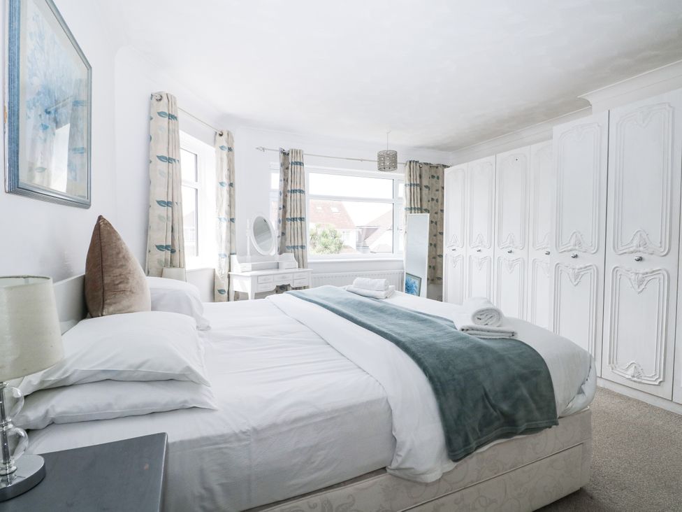 A bedroom with a bed and wardrobe at Sea Dreams in Goring-By-Sea