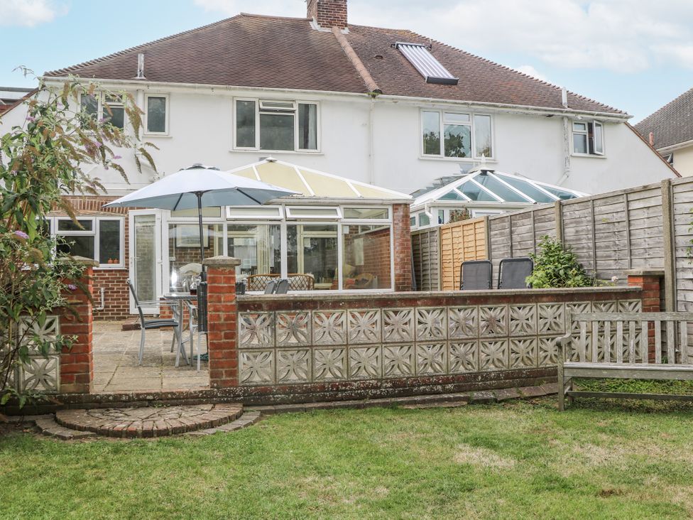 A garden with seating area and a house in the background at Sea Dreams in Goring-By-Sea
