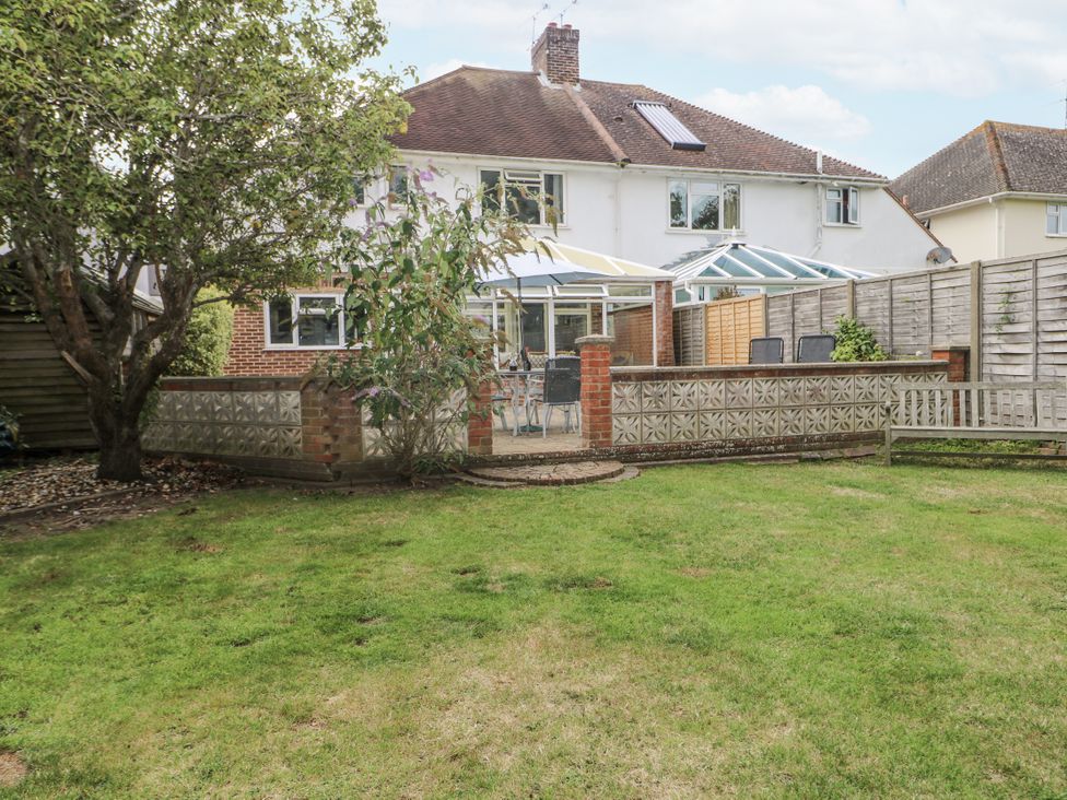 A garden with a glasshouse and seating area at Sea Dreams in Goring-By-Sea