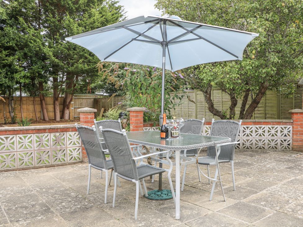 A garden with a table and chairs under an umbrella at Sea Dreams in Goring-By-Sea