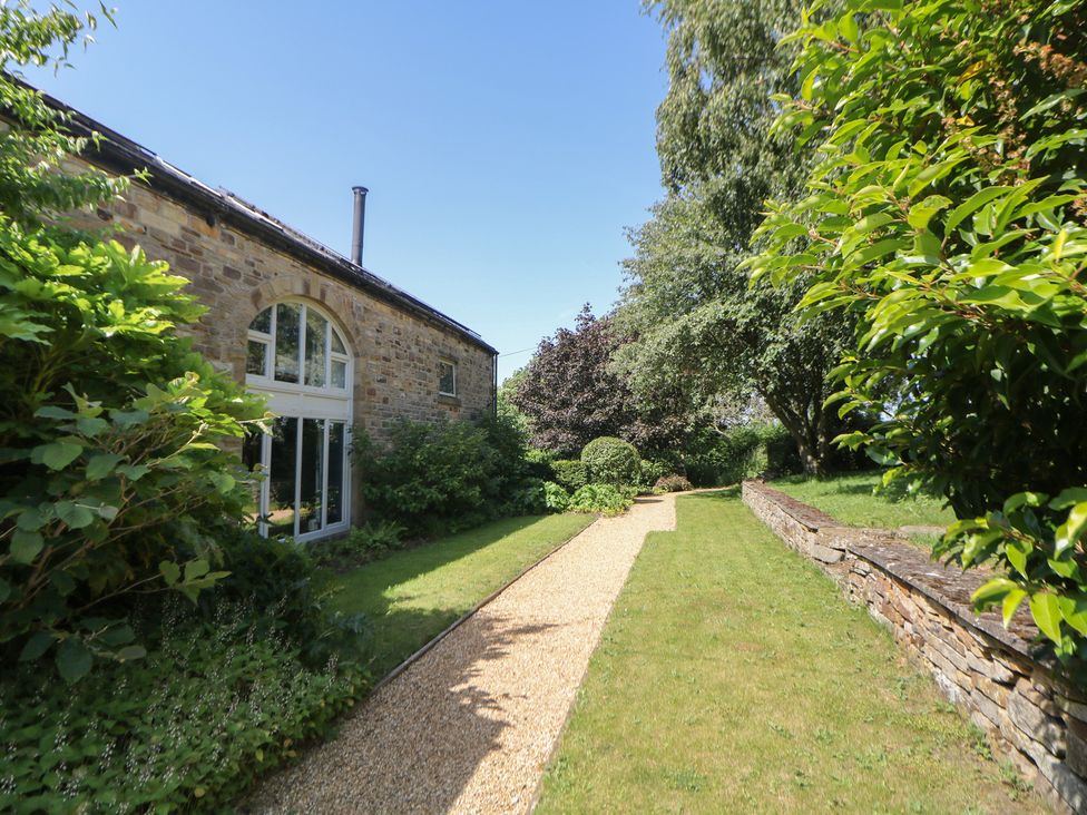 A garden with a pathway and greenery at Overlea Cowshed in Hayfield