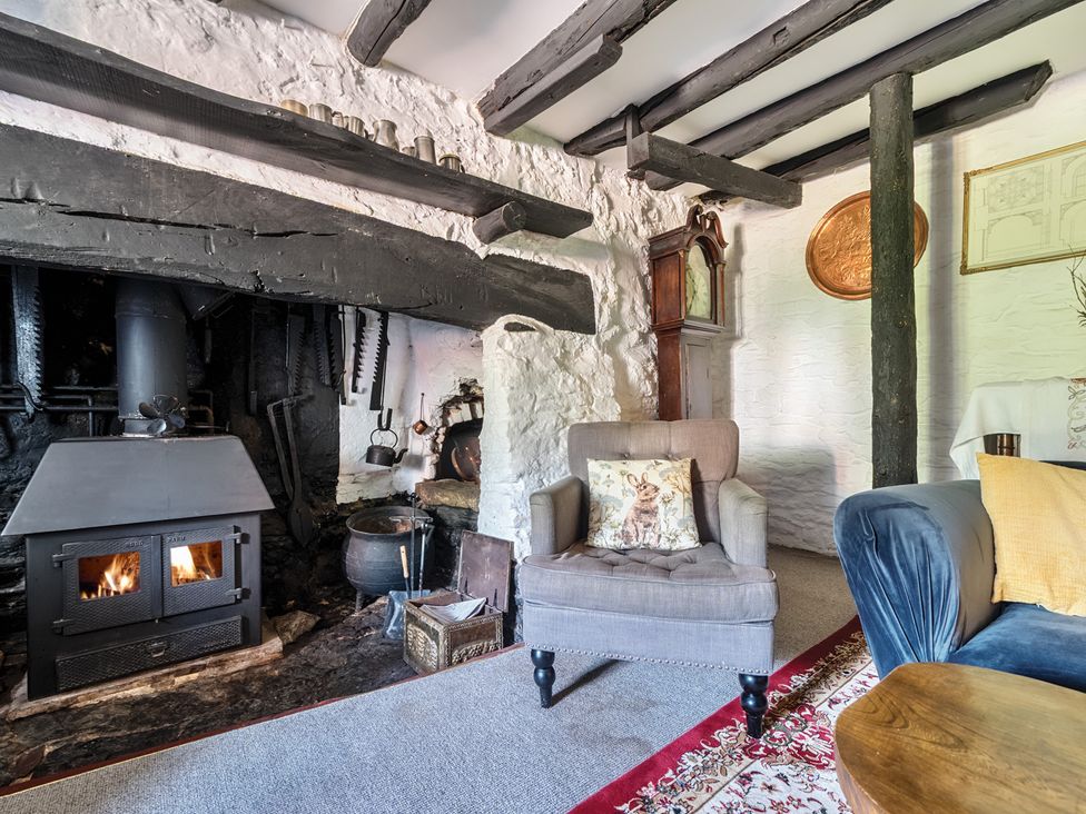 A living room with a fireplace and armchair at The Old Church House in Torbryan