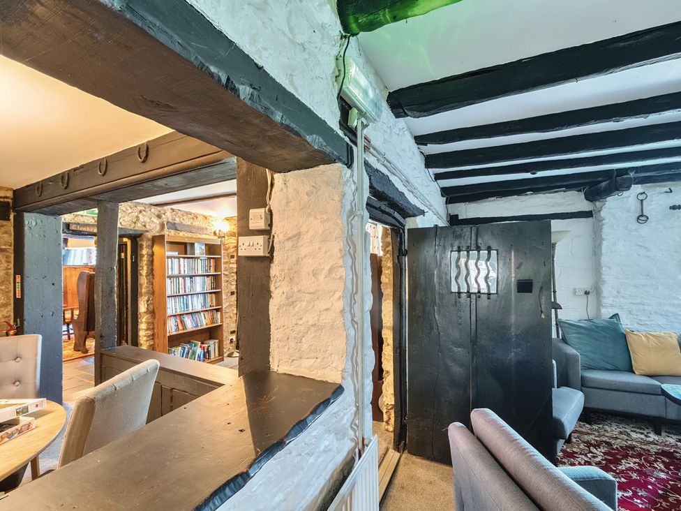 A living room with a door and bookshelf at The Old Church House in Torbryan