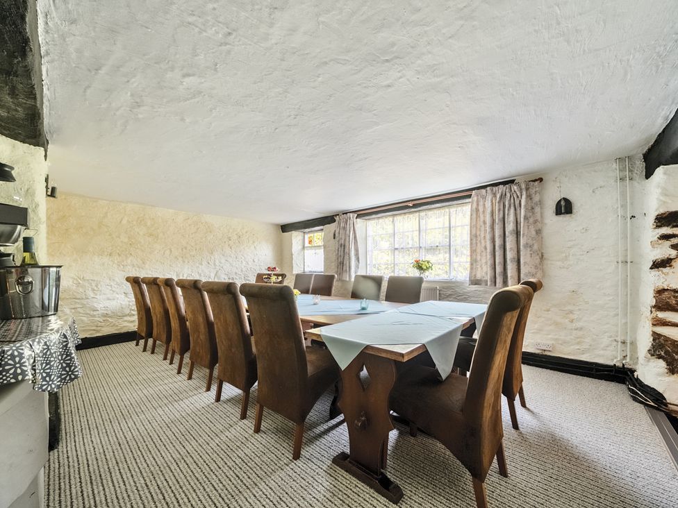A dining room with a long table and chairs at The Old Church House in Torbryan