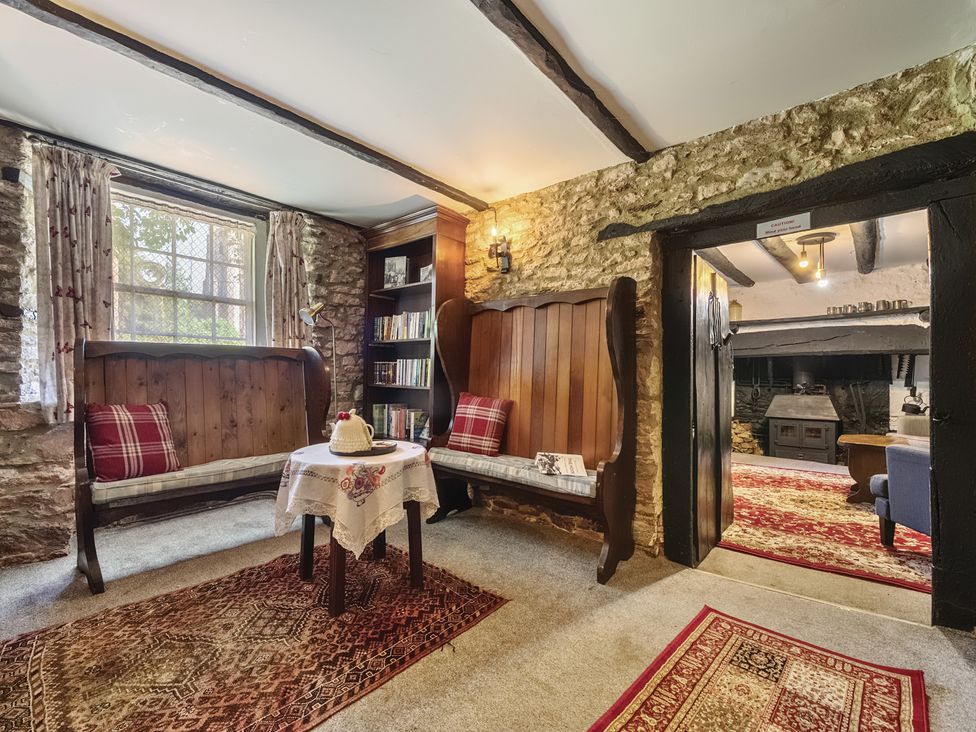 A snug with seating and a bookshelf at The Old Church House in Torbryan