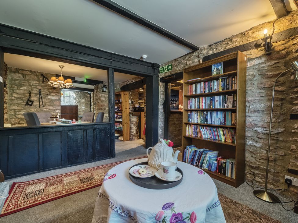A snug with a table and bookshelf at The Old Church House in Torbryan