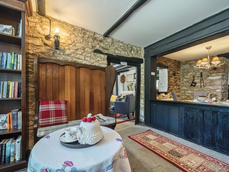 A living room with a bookshelf and a table at The Old Church House in Torbryan