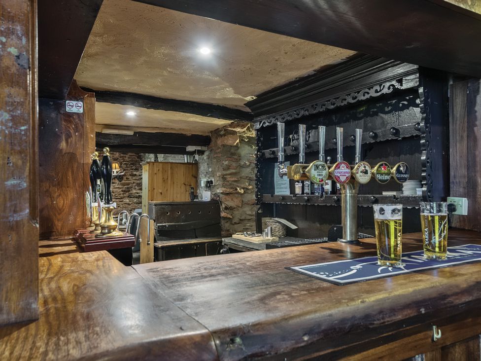 A bar counter with beer taps and glasses of beer at The Old Church House in Torbryan