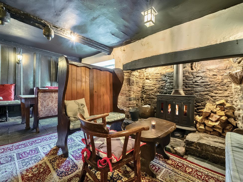 A snug with a fireplace, wooden furniture, and a carpet at The Old Church House in Torbryan