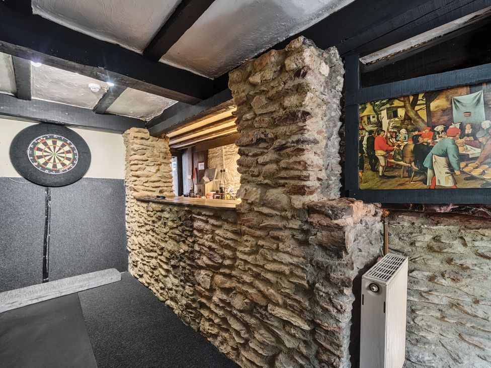 A snug with a dartboard and stone wall at The Old Church House in Torbryan