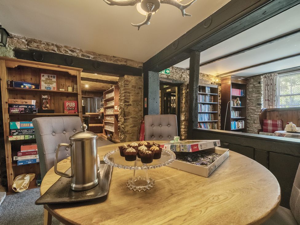 A snug room with a table of cupcakes and a bookshelf at The Old Church House in Torbryan