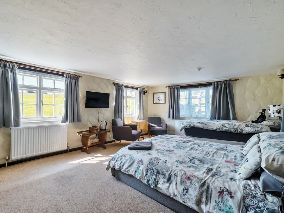 A bedroom with two beds and a television at The Old Church House in Torbryan