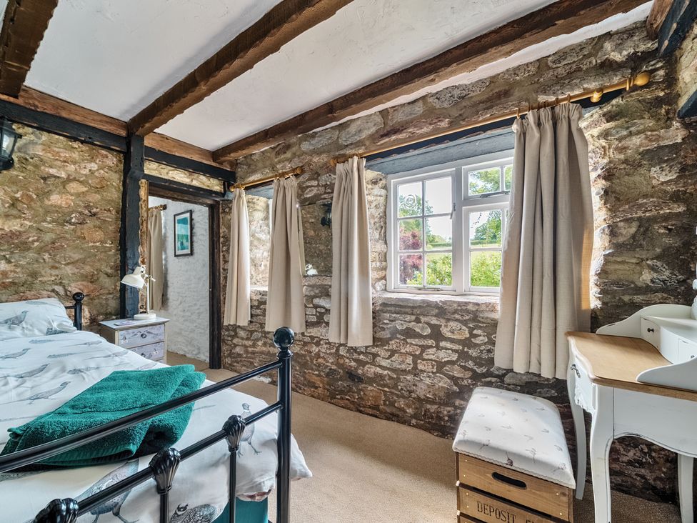 A bedroom with a bed and bench at The Old Church House in Torbryan