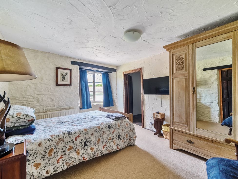 A bedroom with a bed and wardrobe at The Old Church House in Torbryan