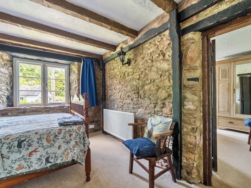 A bedroom with a bed, chair, and wardrobe at The Old Church House in Torbryan