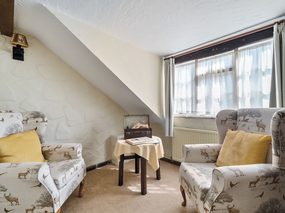 A snug with two armchairs and a small table at The Old Church House in Torbryan