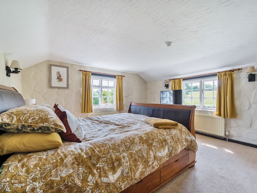 A bedroom with a bed and windows at The Old Church House in Torbryan