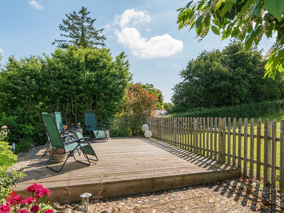A decking area with chairs and flowers at The Old Church House in Torbryan