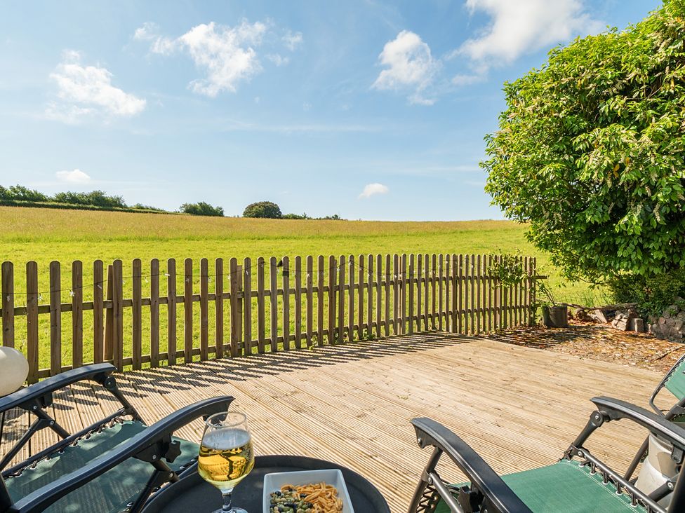 A deck area with chairs and food overlooking a field at The Old Church House in Torbryan