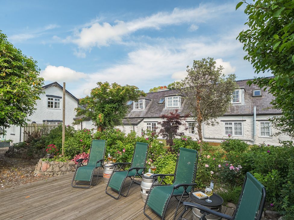 A garden with green chairs and flowers at The Old Church House in Torbryan