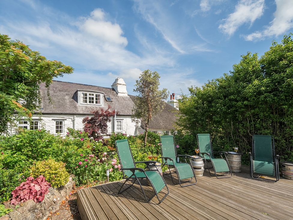 A deck with green chairs and flowers at The Old Church House in Torbryan