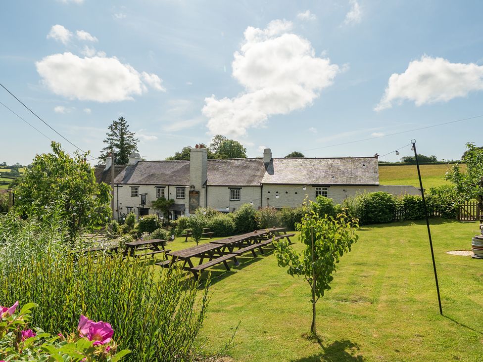 A garden with picnic tables and a house at The Old Church House in Torbryan