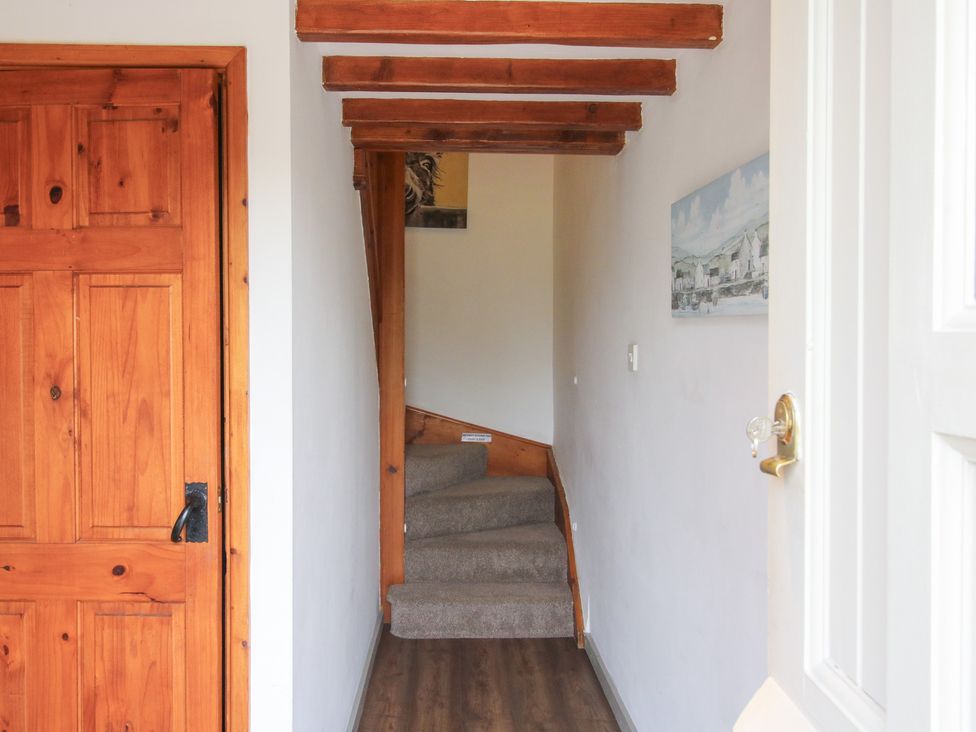 A hallway with a staircase and wooden door at Old Hall Barn 3 Church Stretton