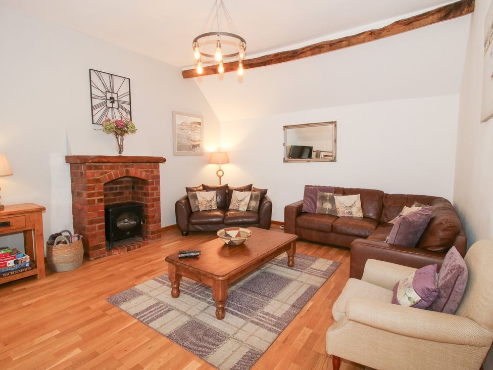 A living room with a fireplace and sofas at Old Hall Barn 3 Church Stretton