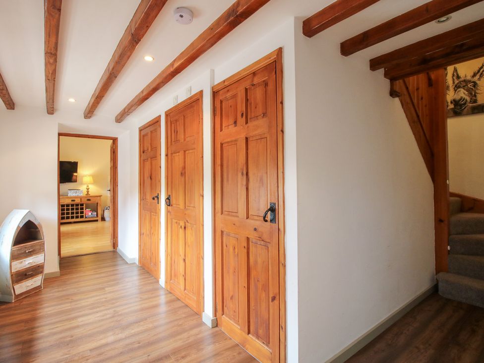 A hallway with wooden doors and a staircase at Old Hall Barn 3, Church Stretton