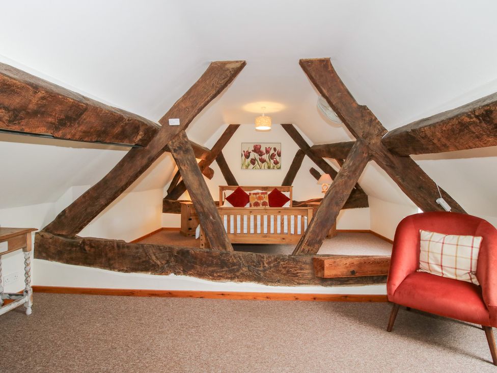 A loft with wooden beams and a bed at Old Hall Barn 3, Church Stretton