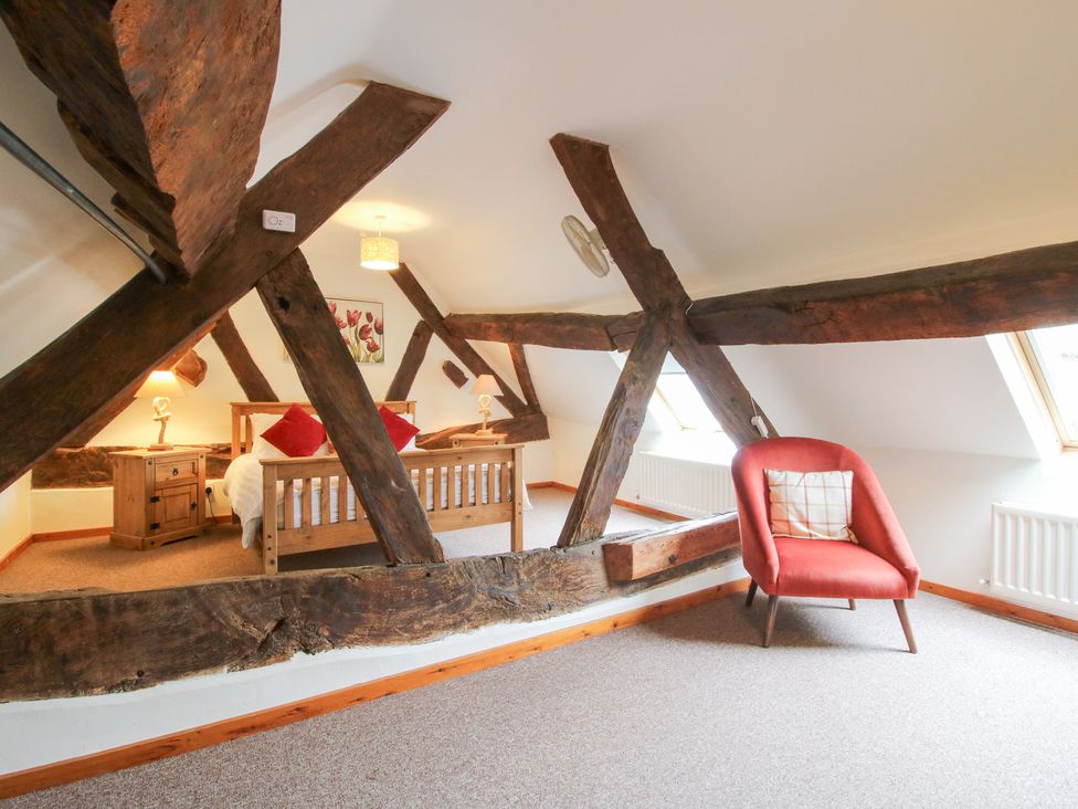 A bedroom with a bed and an armchair at Old Hall Barn 3, Church Stretton