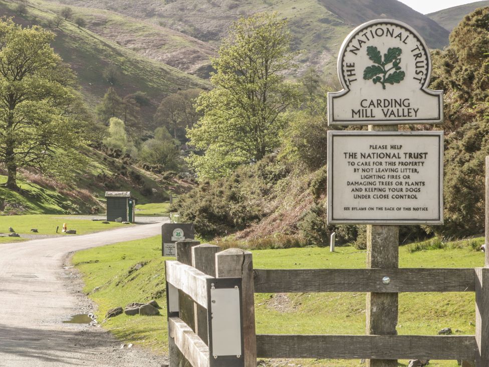 A sign at Carding Mill Valley with a view of trees and hills