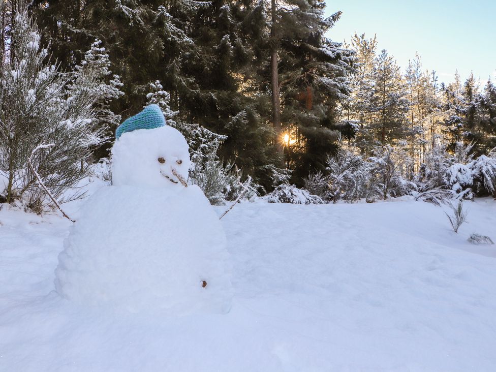 A snowman with a hat in a snowy landscape at Otter Lodge Feshiebridge near Aviemore