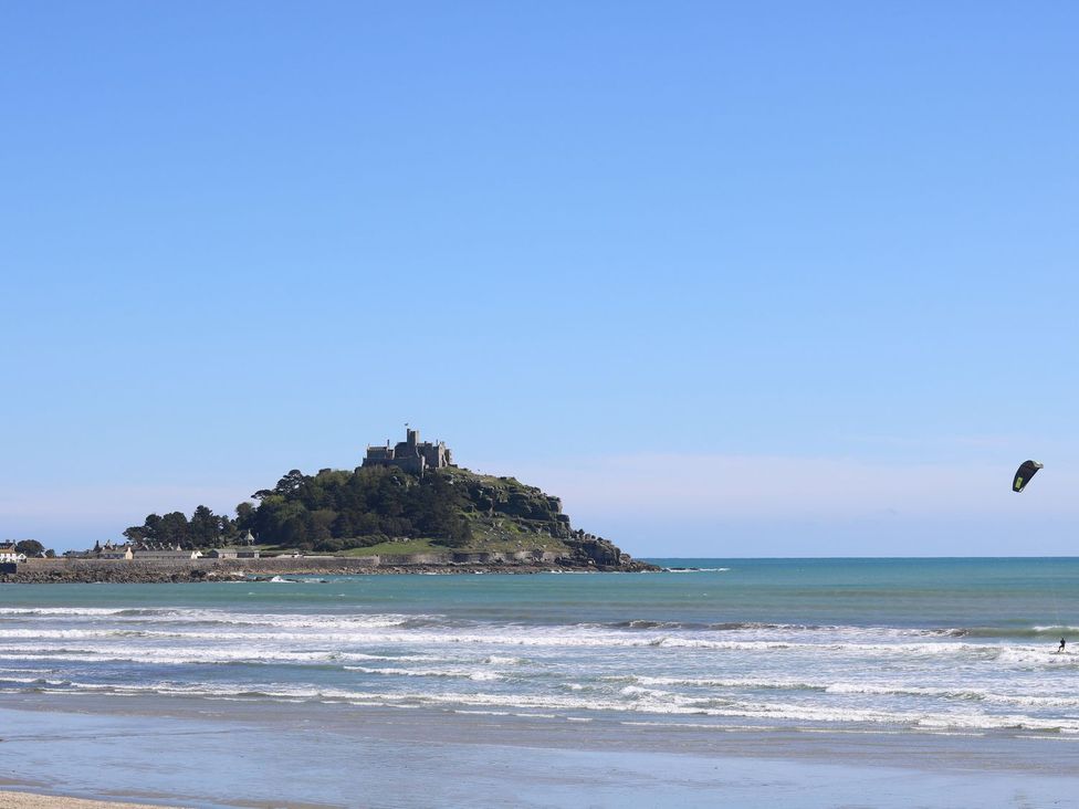 A beach scene with a castle on an island and a kite surfer at Kernyk Rinsey near Porthleven