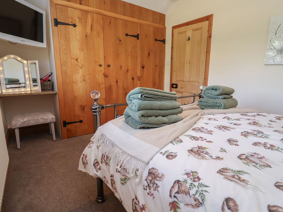 A bedroom with a bed and towels at Ash Farm Cottage in Lixwm near Caerwys