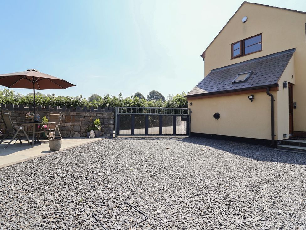 An outdoor area with a table and chairs under an umbrella at Ash Farm Cottage in Lixwm near Caerwys