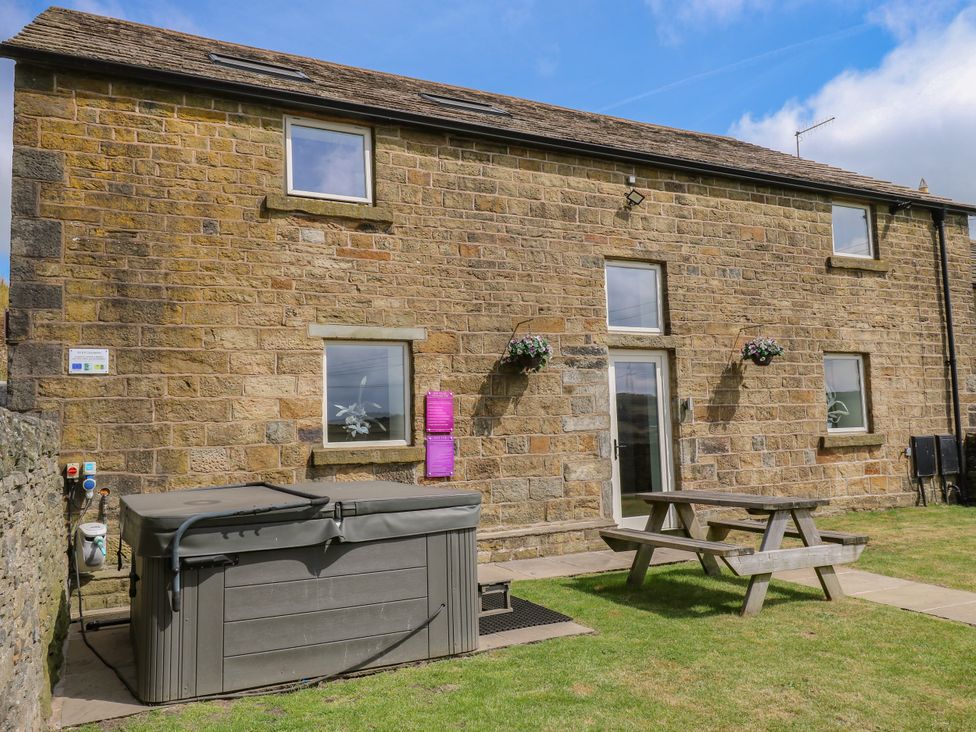 An outdoor area with a hot tub and dining table at Upper House Barn in Delph