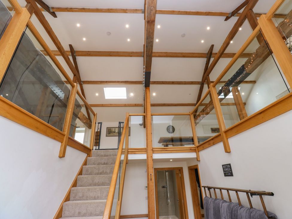 A hallway with stairs and glass railing at Upper House Barn in Delph