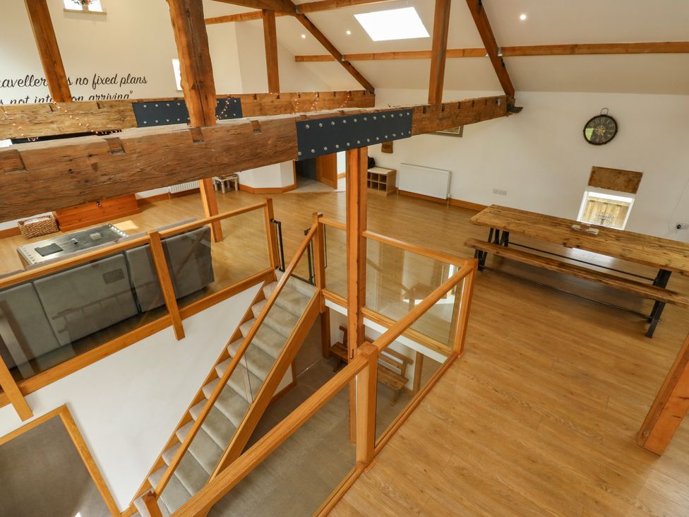 A living room with wooden beams and a dining table at Upper House Barn in Delph