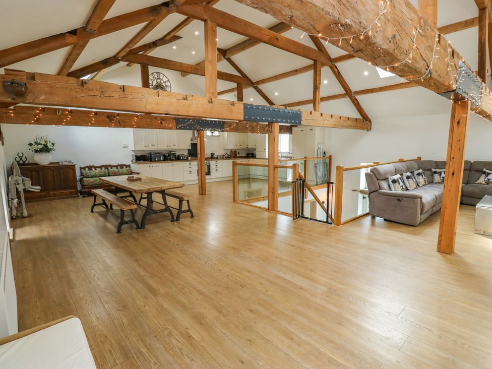 A living room with wooden beams and a kitchen at Upper House Barn (Saddleworth) Delph